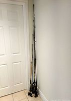 Photo showing five fishing rods standing upright against a wall, displaying overall length and condition.
