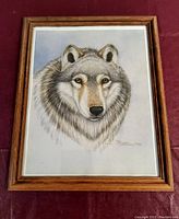 Full view of framed wolf art print with light blue-gray background and wood frame.