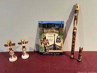 Photo showing entire lot including two painted totem salt and pepper shakers, mini totem figure, carved wooden whistle and small painted figure, and a commemorative book about totem poles.