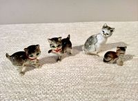 Four vintage Japanese porcelain kitten items including two salt and pepper shakers and two figurines arranged on fabric surface