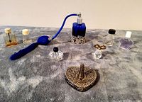 Full lot showing the blue atomizer, assorted vintage perfume bottles, ring stand, and nail polish bottle arranged on a fabric surface.