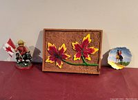 Three vintage RCMP and Canadian collectibles including wooden maple leaf plaque, teddy bear figure on horse, and RCMP pin dish.