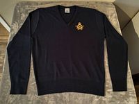 Front view of navy blue soft knit RCAF pullover sweater laid flat on surface, showing embroidered patch on chest and V-neck neckline