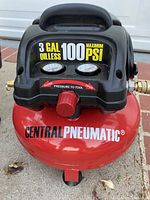 Front view of red Central Pneumatic 3 gallon oil-less air compressor showing pressure gauges and control knob
