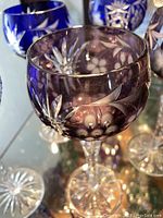 Amethyst purple cut-to-clear wine glass with floral and geometric cuts on twisted clear stem and starburst base