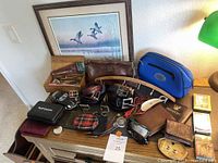 Full layout of gentlemen's collection items including belts, dopp kits, wallets, grooming tools, framed artwork and accessories.
