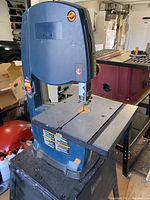 Ryobi 9-inch band saw front and top angled view mounted on black rolling tool stand.