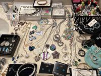 Countertop covered with assorted necklaces, earrings, bracelets, pendants in trays and loose