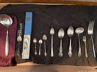 Wide view of all spoons, ladles, forks, and butter utensil laid out side by side showing variety and sizes.