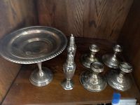 Photo of a sterling silver weighted base pedestal bowl, a pair of salt and pepper shakers, and four candleholders with tarnish and signs of use.