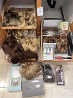 Overview of wigs and hair pieces laid out showing variety of colors and packaging