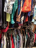 Photo showing a rack of assorted women's casual tops and knits in multiple colors and patterns hanging on hangers.