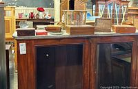 Photo showing multiple wood boxes, a hammered aluminum planter, candle holder, and VHS tape on a wooden cabinet.
