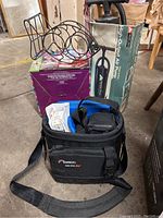 Overview of the lot including the camera bag with Olympus digital camera inside, the boxed air pump, a wire fish-shaped rack, and the boxed cotton candy maker.