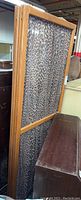 Side angled photo of the four-panel folding privacy screen showing wooden frame and leopard print fabric curtains.