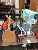 Wide view of the lot showing carpenter's tote, clamps, steel mailbox, box with lamp parts, and kitchen utensils