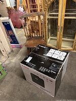 Photo showing the laser printer box and vintage wooden dining chair together in storage area.