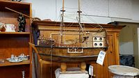 Front view of the vintage wooden model ship lamp showing the entire ship, masts, rigging, and wooden stand.