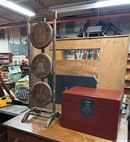 Wide view of the folding Bicentennial themed plant stand with three circular illustrated panels and red lacquered wooden box adjacent on table surface.