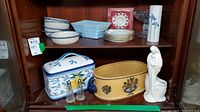 Full shelf display including stacked bowls, plates, figurine, ceramic containers and planters noting Noritake and Haeger pieces.