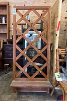 Full view of wooden wall mounted trellis style peg rack with lower shelf, showing overall construction and condition.