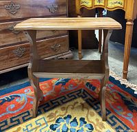 Front view of wooden side table with book rack tier showing rectangular tabletop and lower shelf.