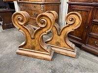 Pair of wooden scroll style table legs shown from front angle, displaying overall design and condition with scratches.