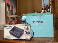 Photo showing boxed vintage GE Answering System and blue Zosi Wireless security system box together.
