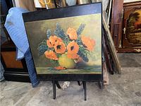 Front view showing the floral artwork on the table top in an orange and green floral arrangement on a yellow vase, with a black wooden border.