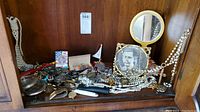 Full view of lot showing multiple watches, costume jewelry, framed photo, hand mirror, and other small items inside wooden cabinet