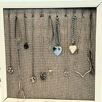 Display frame holding 15 vintage necklaces and bracelets hung vertically with heart-shaped pendants, various chains and charms visible.