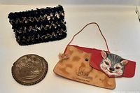 Three vintage change purses: black/beige sequined clutch, cat wristlet with detached flap, and brown embossed round coin purse.