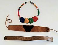 Three vintage chokers laid out: multicolor fabric choker with flower details on top, wide brown suede leather choker with black butterfly in the middle, narrow brown leather choker with flower embossing at bottom