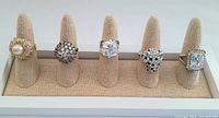 Front view of all five vintage cocktail rings on display stand showing design and condition