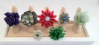 Photo showing all 7 vintage chunky floral rings on a beige ring display stand.