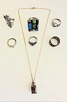 All 7 pieces of vintage .925 sterling silver jewelry arranged and visible including rings and necklace with amethyst pendant.