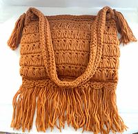 Front view of vintage burnt orange wool hobo tote handbag showing crochet pattern and fringe bottom