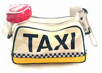 Main front view of cream-colored vinyl handbag with large black 'TAXI' text and checkerboard stripe detail, showing attached red circular change purse with white 'FOR HIRE' text attached to top left corner.