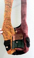 Photo showing the bag's long strap, multi-color wool fabric with buttoned pockets in colors black, green and brown, and the textured woven pattern.