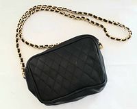 Black vintage handbag showing front quilted design and chain strap.