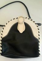 Front view of the black and white handbag showing striped trim and characterizing buckle flap closure.