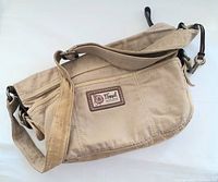 Beige Fossil canvas shoulder handbag shown flat with strap and external zippered pocket visible