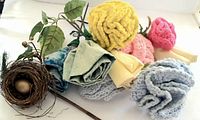 Overview of all items including the crochet flowers, cloth flowers, leaf branch, and bird nest with egg.