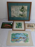 Full view of the five framed watercolor paintings arranged on floor against a wall, showing varying subjects and sizes