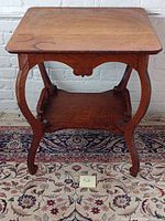 Front view of the antique oak bow legged side table showing the rectangular top, bow legs, and lower shelf.