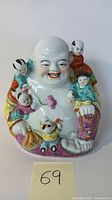 Front view of a glossy ceramic Happy Buddha figure surrounded by five children figures, showing hand-painted detailed facial features and colorful clothing.