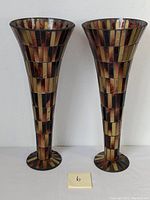 Full view of two tall mosaic vases with warm colors and narrow bases