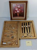 Photo showing the full display of framed oil painting and two wooden trays containing assorted costume jewelry and watches.