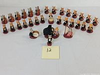 Wide view of 32 vintage miniature cast iron mice arranged as orchestra on white surface.