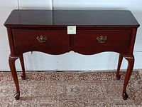 Full frontal view of the vintage Bombay console table showing two drawers with brass handles, glossy wooden top, and cabriole legs.